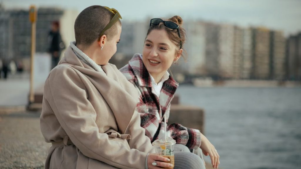 Two women enjoying a conversation by the seaside with a coffee. A joyful, relaxed moment.