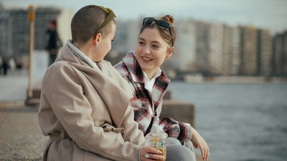 Two women enjoying a conversation by the seaside with a coffee. A joyful, relaxed moment.