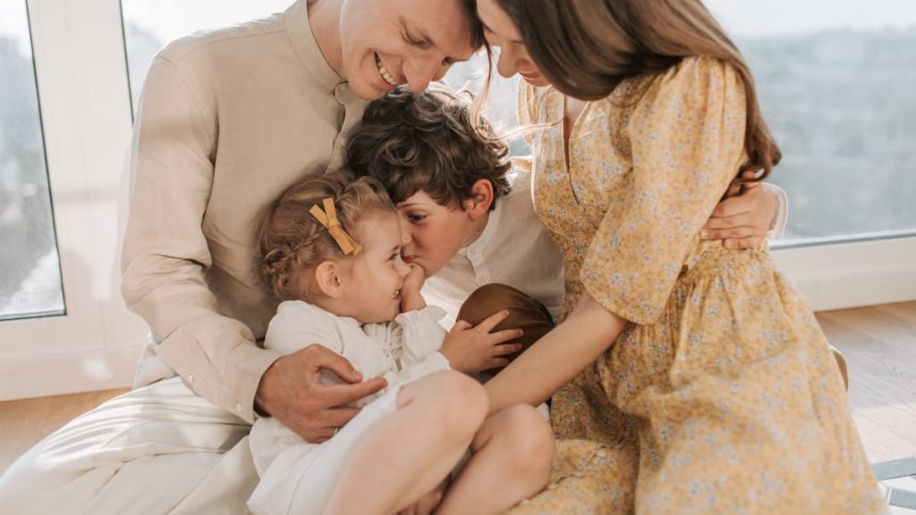 A happy family of four sitting together and sharing a loving moment indoors.